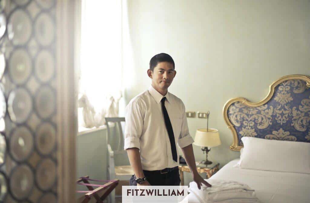 Ethnic male maid arranging hotel room