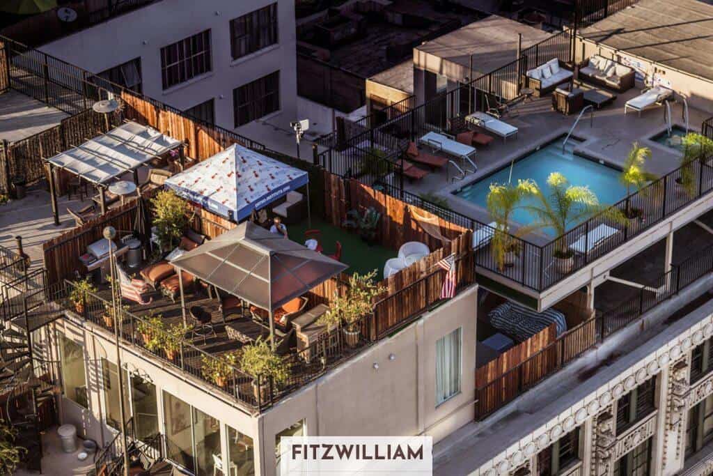 An aerial view of a stylish rooftop terrace with a pool and seating area in a city setting.