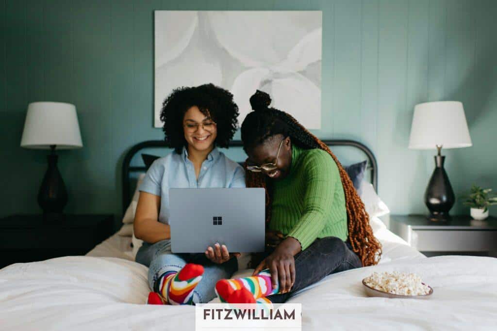 a woman sitting on a bed using a laptop